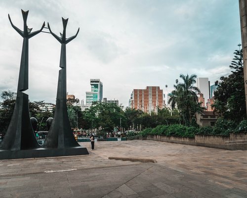A green urban park space in Medellin with walkways and trees under clean skies