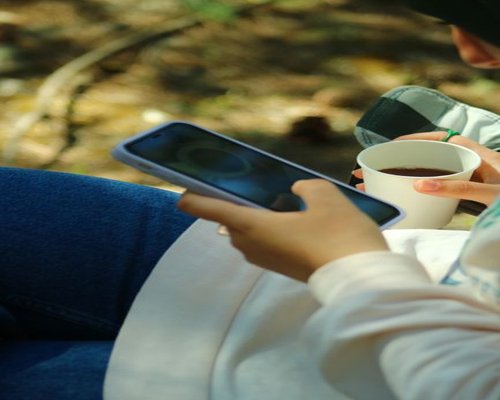 A person holding a smartphone horizontally at a comfortable viewing height outdoors